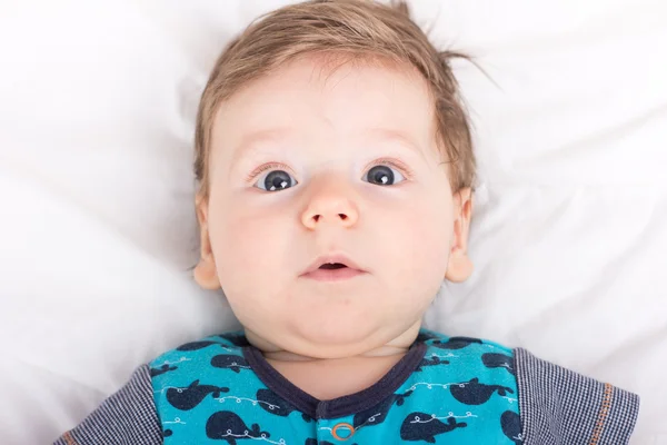 Portret uśmiechniętego dziecka. Dziecko na białym łóżku. Przystojny chłopak. — Zdjęcie stockowe