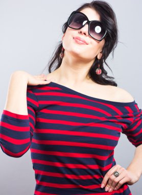 Güzel esmer kırmızı çizgili mavi bir elbise içinde. Moda. Güneş gözlüklü genç bir kızın portresi.