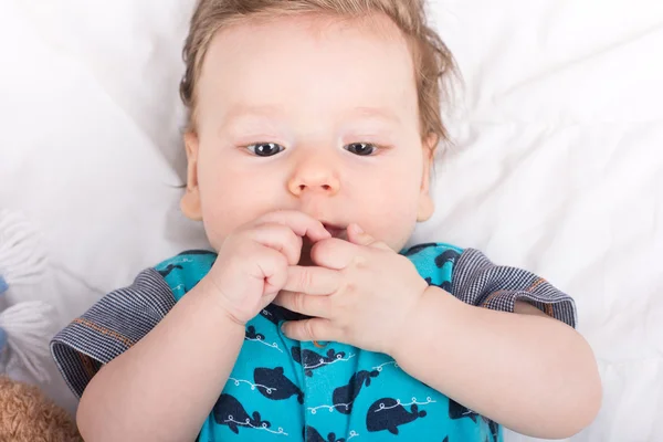 Portret van een glimlachend kind. Een kind op een witte bed. Knappe jongen. — Stockfoto