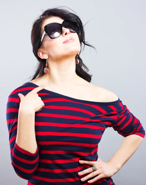 Vacker brunett i en blå klänning med röda ränder. Fashion. Porträtt av en ung flicka i solglasögon. — Stockfoto