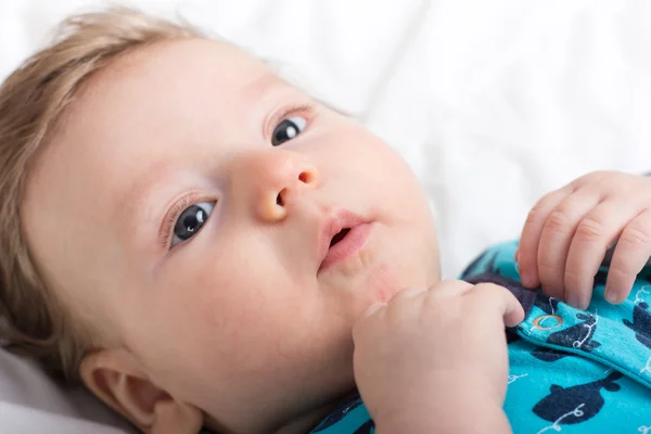 Portret van een glimlachend kind. Een kind op een witte bed. Knappe jongen. — Stockfoto