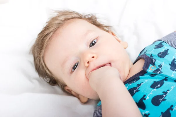 Portret van een glimlachend kind. Een kind op een witte bed. Knappe jongen. — Stockfoto