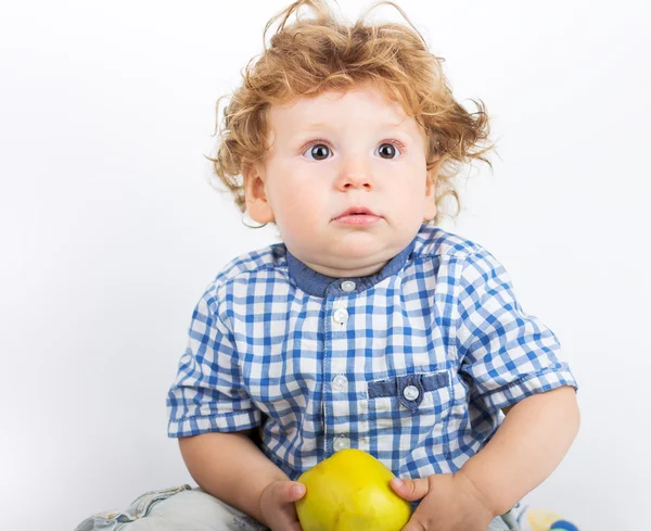 Маленький мальчик держит зеленое яблоко на белом фоне — стоковое фото