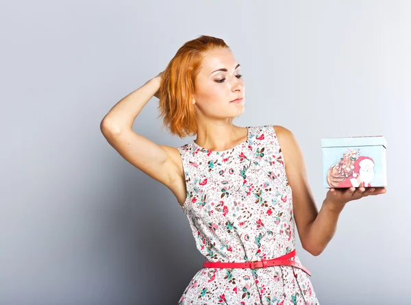 Seorang gadis ramping cantik dengan kotak hadiah di tangannya. Gadis Happy dengan hadiah pada latar belakang abu-abu. Tahun Baru. Xmas — Stok Foto