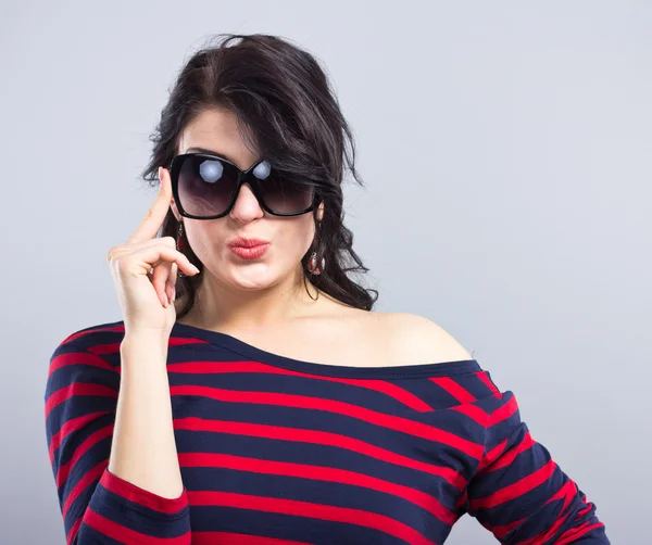 Schöne Brünette in einem blauen Kleid mit roten Streifen. Mode. Porträt eines jungen Mädchens mit Sonnenbrille. — Stockfoto