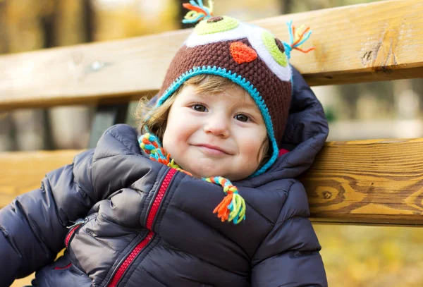 Cute baby in a funny hat on a walk. Autumn promenade. Headdress. A cap — Stockfoto