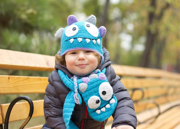 Cute baby in a funny hat on a walk. Autumn promenade. Headdress. A cap — Stockfoto