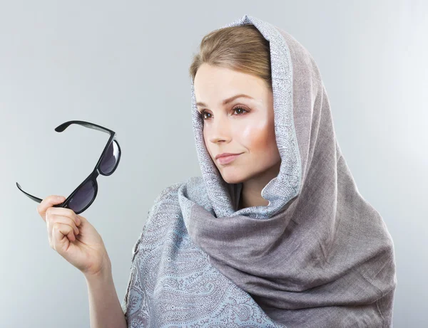 Vacker ung kvinna i en broderad sjal och solglasögon på en grå bakgrund — Stockfoto