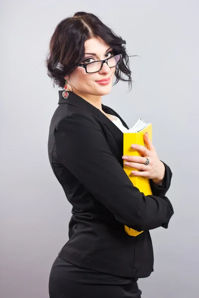 Portrait of beautiful brunette in glasses with a yellow folder in her hands. — Stock Photo, Image