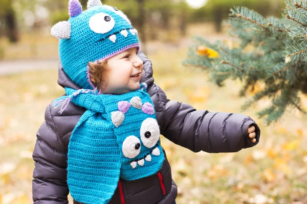 Happy baby i en rolig hatt på en promenad. Gångavstånd utomhus på hösten. Höstlöv — Stockfoto