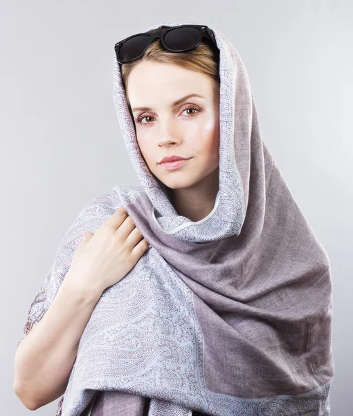 Krásná mladá žena v vyšívaný šátek a sluneční brýle na šedém pozadí — Stock fotografie