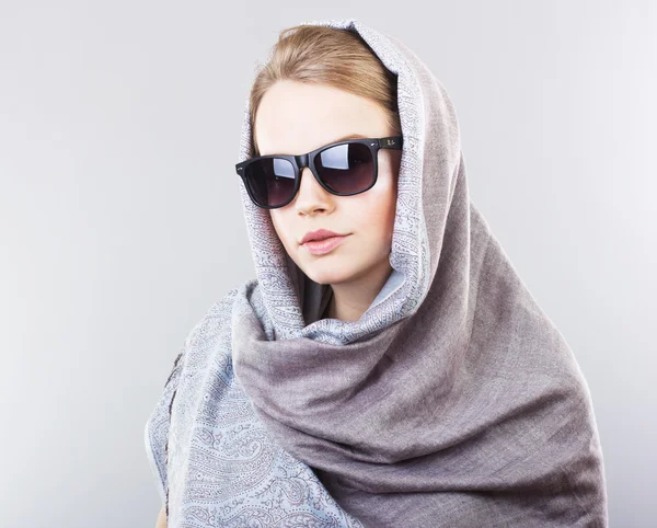 Krásná mladá žena v vyšívaný šátek a sluneční brýle na šedém pozadí — Stock fotografie