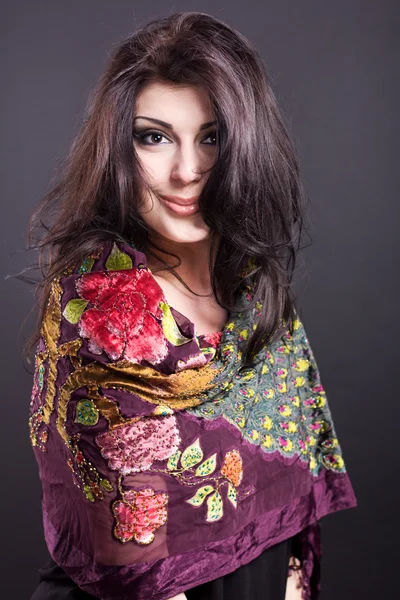 Attractive brunette in a bright attire on a black background. Fashion portrait. Portrait of a beautiful brunette. Bright embroidered handkerchief