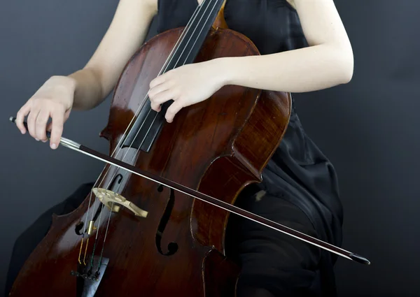 Une jeune fille joue du violoncelle dans le noir. Main sur le violoncelle — Photo