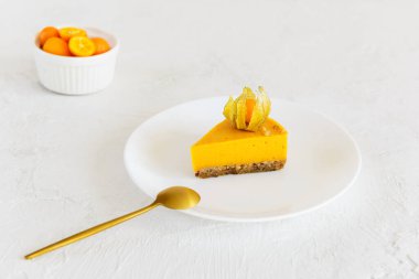 Bir dilim balkabağı turtası, tabakta fizsalis ile süslenmiş. Şeker, laktoz, glütensiz.