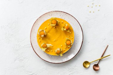 Beyaz bir masanın üzerinde fizsalis ile süslenmiş balkabağı pastası. Şeker, laktoz, glütensiz. Yatay yönelim, üst görünüm.