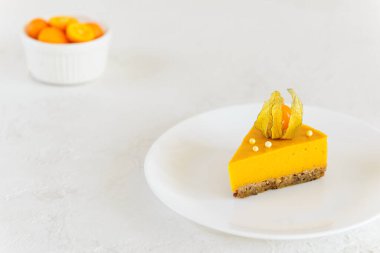 Beyaz tabakta physalis olan bir dilim balkabaklı cheesecake..