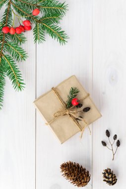 Noel ve Yeni Yıl için bir kutuda bir köknar dalı ve ahşap bir masanın üzerinde koniler. Yatay yönelim, üst görünüm.