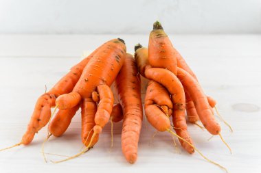 Ahşap bir masada bir avuç çirkin havuç. Çirkin sebze konsepti.