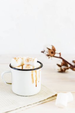 Şekerlemeli sıcak çikolata ve beyaz fincanda tarçın. Arka planda damlalar var..