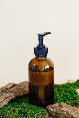 Cam şişedeki kozmetik ürünü ağaç kabuğu ve yosun üzerinde.