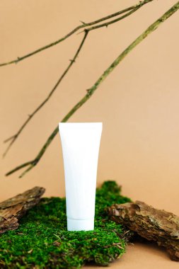 Beyaz plastik tüp, yosun, ağaç kabuğu ve dallı kozmetik ürünleri için. Bir kozmetik ürünün maketi.