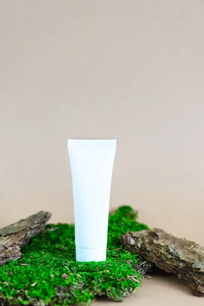 Plastic tube for cosmetics on bark and moss.