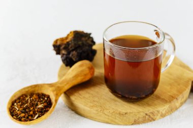 Tahtada kaşıkla cam bardakta Chaga çayı..