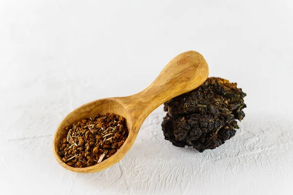 Hafif bir arka planda tahta kaşıkta kurutulmuş chaga çayı..