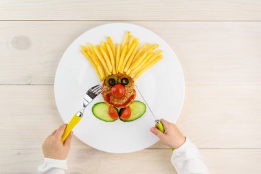 Ahşap bir masanın üzerinde çocuk eli olan bir palyaço şeklinde çocuk maması..