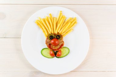 Ahşap bir masada palyaço şeklinde çocuk maması. Yatay yönelim, üst görünüm.