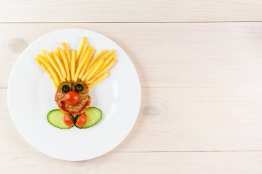 Ahşap bir arka planda palyaço şeklinde çocuk tabağı. Yatay yönelim, boşluğu kopyala.