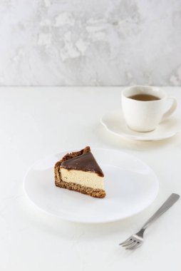 Tuzlu karamelli peynirli keki beyaz tabakta çay eşliğinde dilimle. Vejetaryen tatlı, şeker, glüten ve laktozsuz.