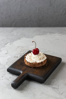 Tahta bir tahtanın üzerinde muzlu, hindistan cevizi kremalı ve kirazlı pasta. Çiğ tatlı, sağlıklı yemek. Şeker, glüten ve laktozsuz.