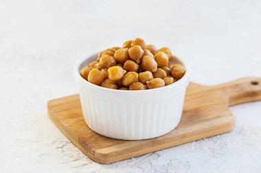 Tahtada beyaz bir kase içinde kaynamış nohut..