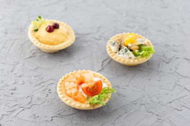 Gri arka planda deniz ürünleri, otlar ve peynirli tart.