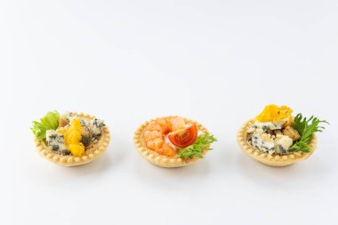 Beyaz arka planda deniz ürünleri, peynir ve otlu tart.