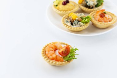 Beyaz bir masada deniz ürünleri, peynir ve otlu tart..