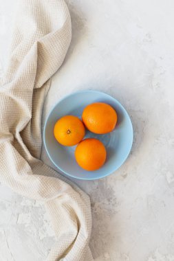 Mavi tabakta, keten havluyla portakallar. Dikey yönelim, üst görünüm.
