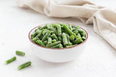 Beyaz bir masada kasede donmuş yeşil fasulye..