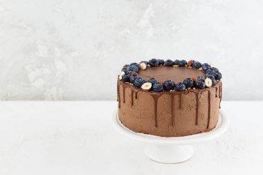 Hafif arka planda yaban mersini ve fındıklı çikolatalı pasta. Yatay yönelim, boşluğu kopyala.