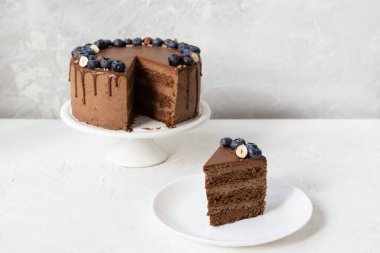 Beyaz bir masada yaban mersini ve fındıklı vejetaryen çikolatalı pasta. Şekersiz, glütensiz ve laktozsuz..