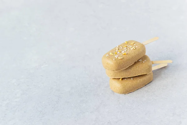 Popsicle with chocolate cashews on a gray background. Sugar, gluten and lactose free. Horizontal orientation, copy space.