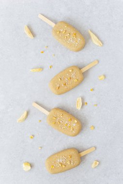 Çikolatalı kaju ve gri arka planda mango parçaları ile vejetaryen dondurması. Dikey yönelim, üst görünüm.