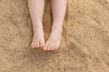 Kumdan bir arka planda bebek ayakları. Yaz arkaplanı.