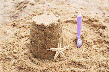 Kumdan bir kalesi ve kumlu bir sahilde bebek küreği olan denizyıldızı..