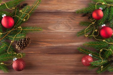 Ahşap arka planda kırmızı Noel topları olan ladin dalları. Noel ve Yeni Yıl konsepti. Yatay yönelim, kopyalama alanı, üst görünüm.