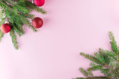 Pembe arka planda kırmızı Noel topları olan dallar. Noel ve Yeni Yıl konsepti. Yatay yönelim, kopyalama alanı, üst görünüm.