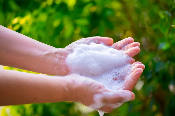 women washing hands with soap and water on green blur background.