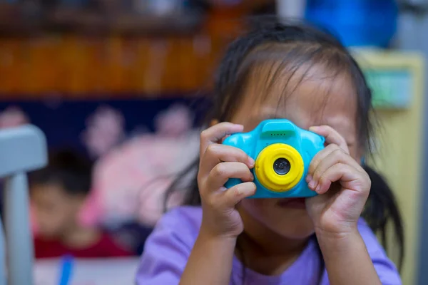 taking pictures of others. Little girl taking picture using toy camera, Photography courses. Camera in hand